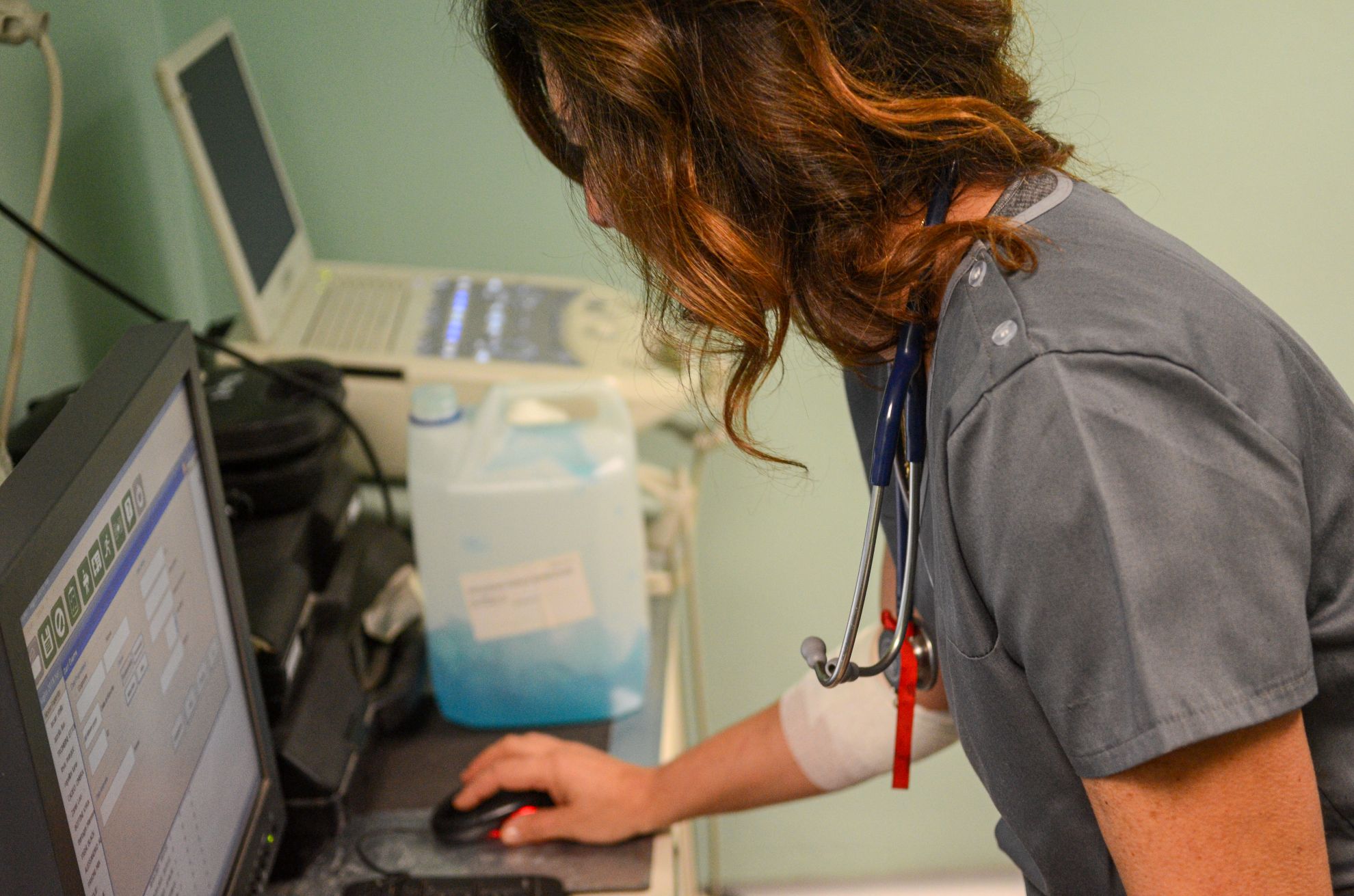 Nurse with stethoscope documenting patient information on a computer in a clinical setting